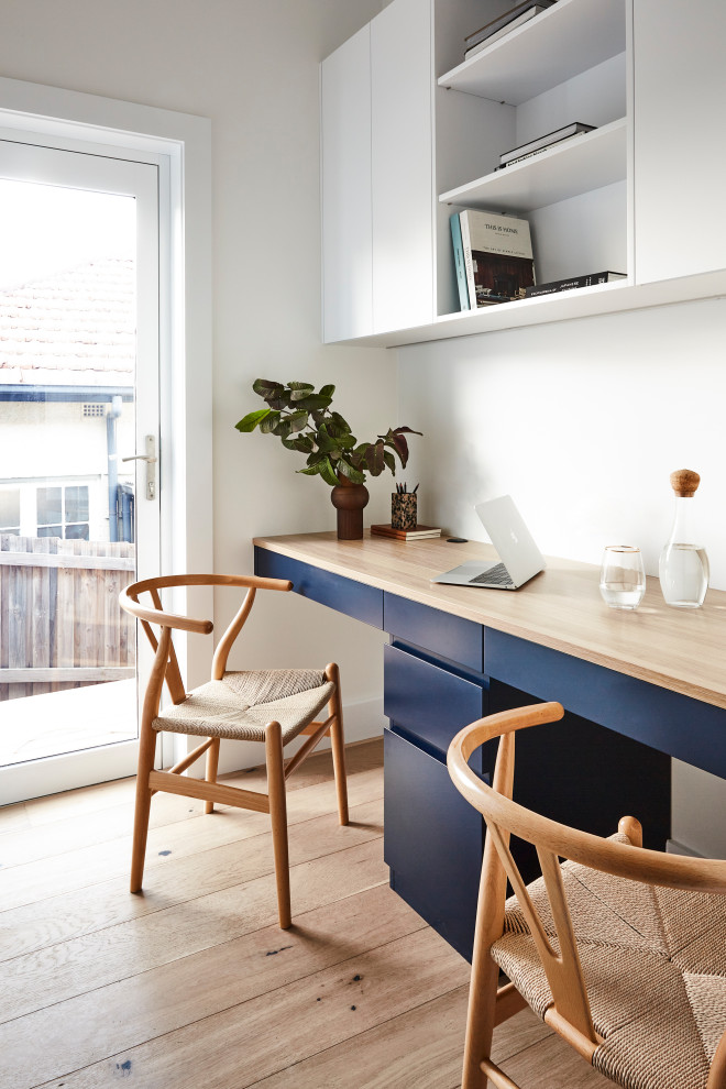 Imagen de despacho escandinavo con paredes blancas, suelo de madera clara y suelo beige
