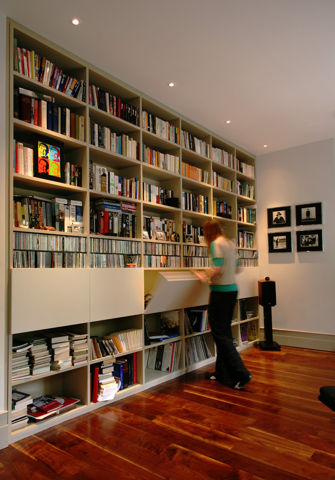 Example of a trendy dark wood floor home office library design in London with white walls