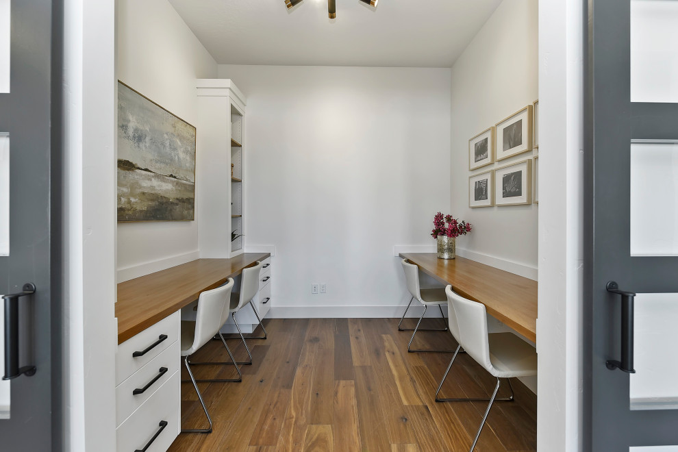 Réalisation d'un bureau tradition de taille moyenne avec un mur blanc, un sol en bois brun et un bureau intégré.