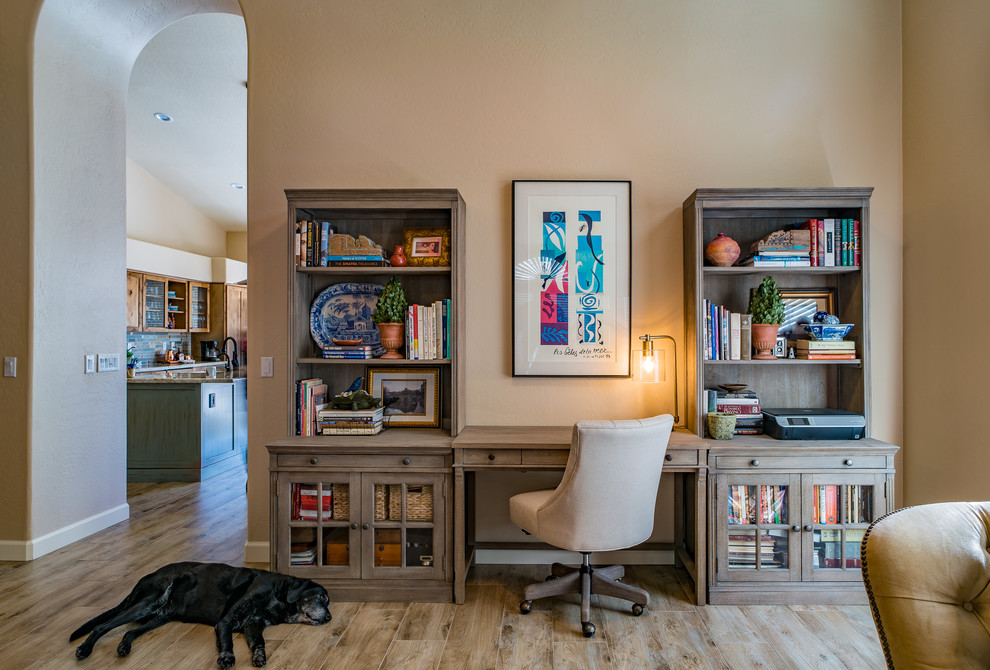 Cette photo montre un bureau montagne de taille moyenne avec une bibliothèque ou un coin lecture, aucune cheminée, un bureau intégré, un sol beige, un mur beige et parquet clair.