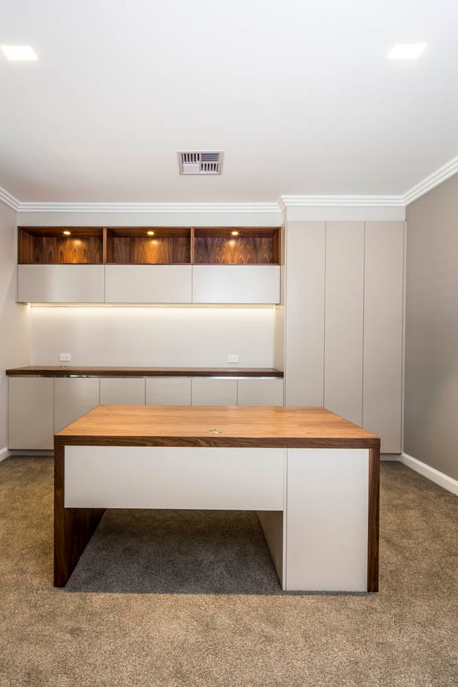 Ejemplo de despacho actual de tamaño medio sin chimenea con paredes beige, moqueta y escritorio independiente