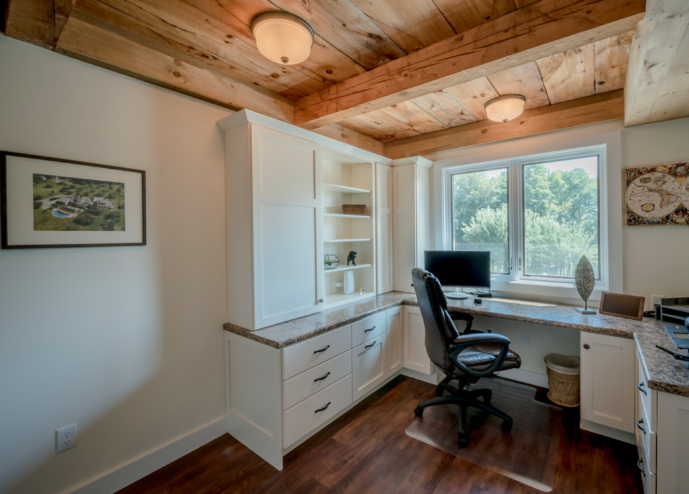 Medium sized rustic study in Boston with beige walls, vinyl flooring, a built-in desk and brown floors.