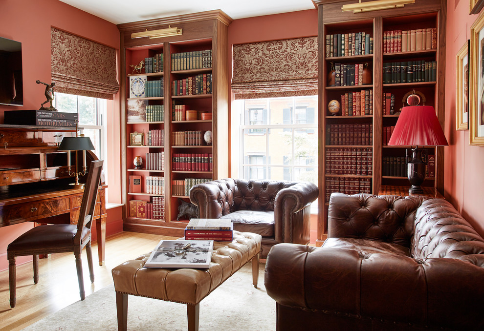 ニューヨークにあるトラディショナルスタイルのおしゃれなホームオフィス・書斎 (ライブラリー、赤い壁、無垢フローリング、暖炉なし、自立型机) の写真