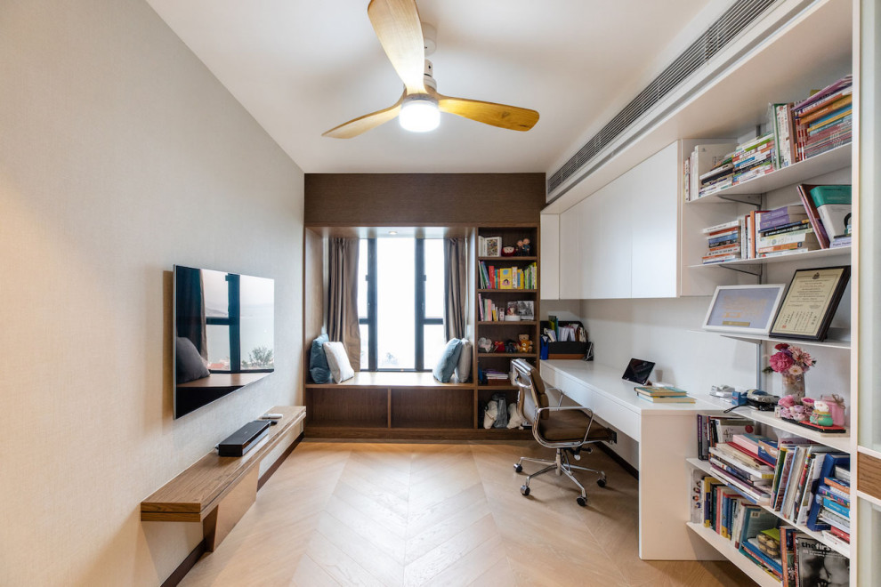 Modelo de despacho contemporáneo de tamaño medio sin chimenea con paredes beige, suelo de madera en tonos medios, escritorio empotrado y suelo beige