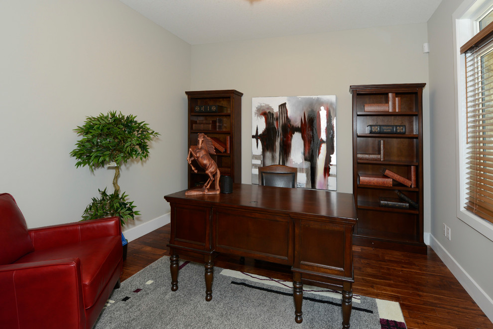 Mittelgroßes Klassisches Arbeitszimmer mit Arbeitsplatz, beiger Wandfarbe, braunem Holzboden und freistehendem Schreibtisch