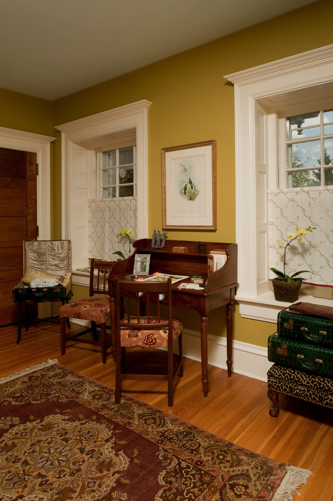 Foto di uno studio classico con pareti gialle, pavimento in legno massello medio e scrivania autoportante