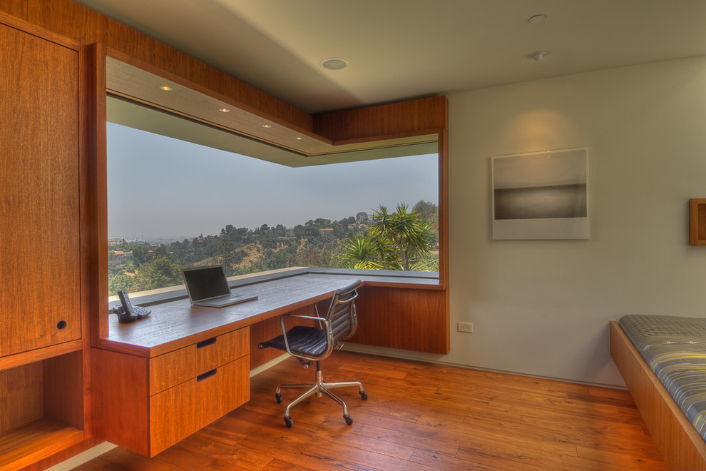 Imagen de despacho minimalista con paredes grises, suelo de madera en tonos medios y escritorio empotrado