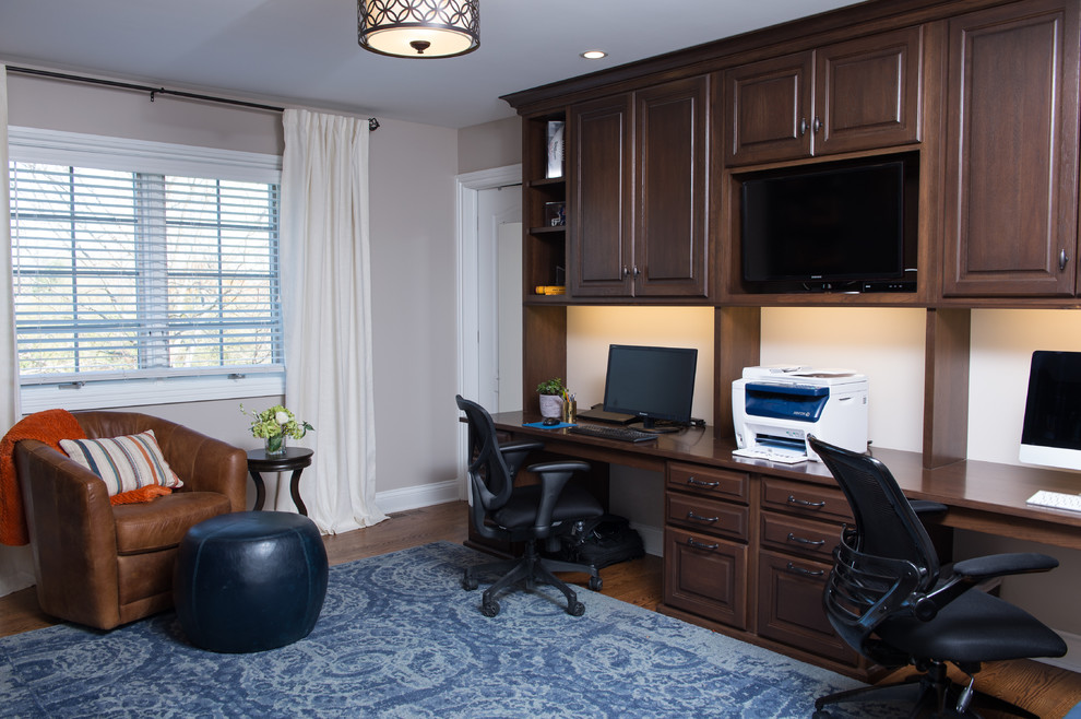Diseño de despacho clásico renovado grande con paredes grises, suelo de madera oscura, escritorio empotrado y suelo marrón
