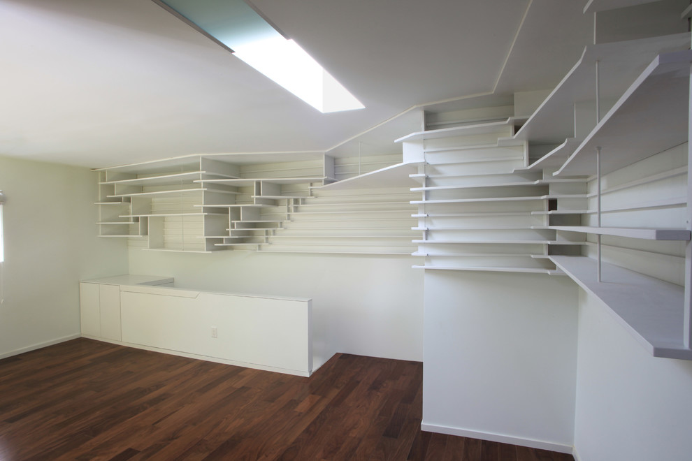 Inspiration för små moderna arbetsrum, med ett bibliotek, vita väggar, mörkt trägolv, ett fristående skrivbord och brunt golv