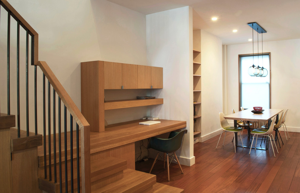 Example of a mid-sized trendy built-in desk light wood floor study room design in New York with white walls and no fireplace