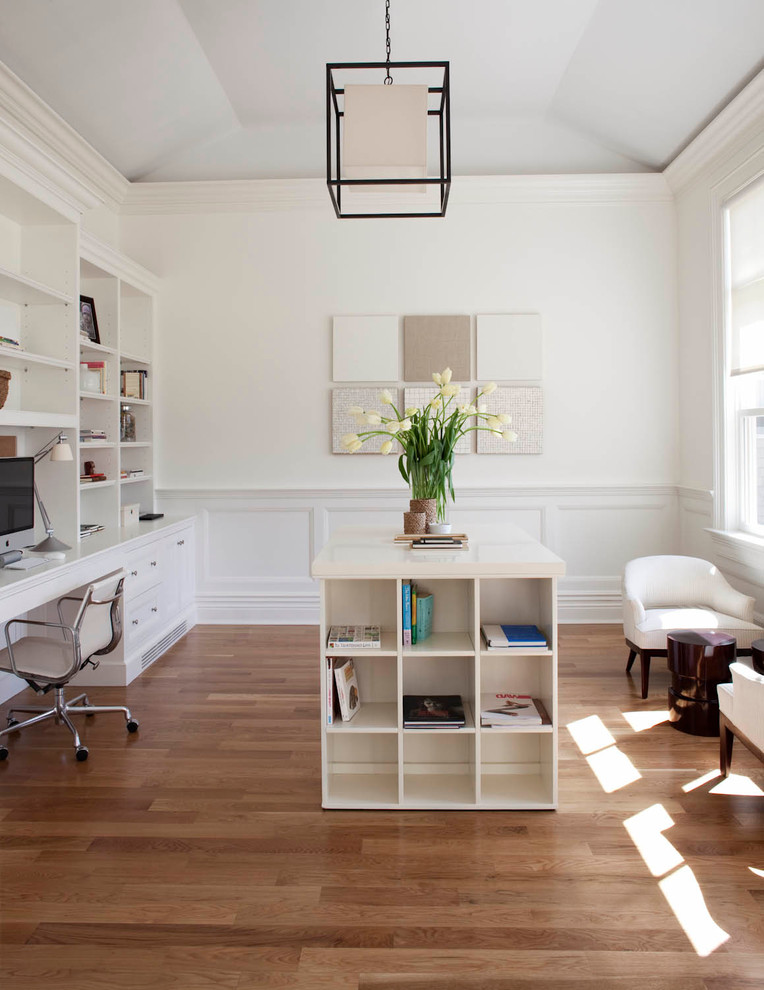 Inspiration för stora klassiska hemmabibliotek, med vita väggar, mellanmörkt trägolv, ett inbyggt skrivbord och beiget golv