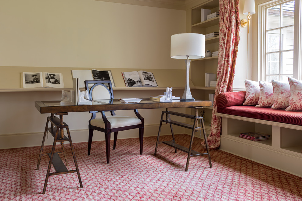 Inspiration för mellanstora klassiska hemmabibliotek, med beige väggar, heltäckningsmatta, ett fristående skrivbord och rött golv