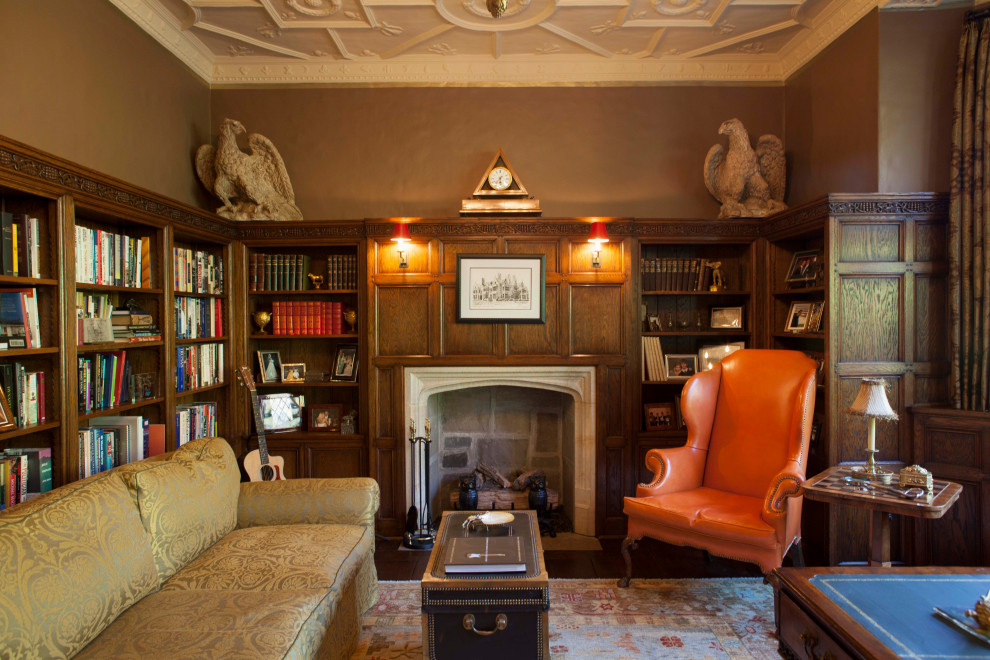 Klassisk inredning av ett arbetsrum, med ett bibliotek, bruna väggar, mörkt trägolv, en standard öppen spis, ett fristående skrivbord och brunt golv