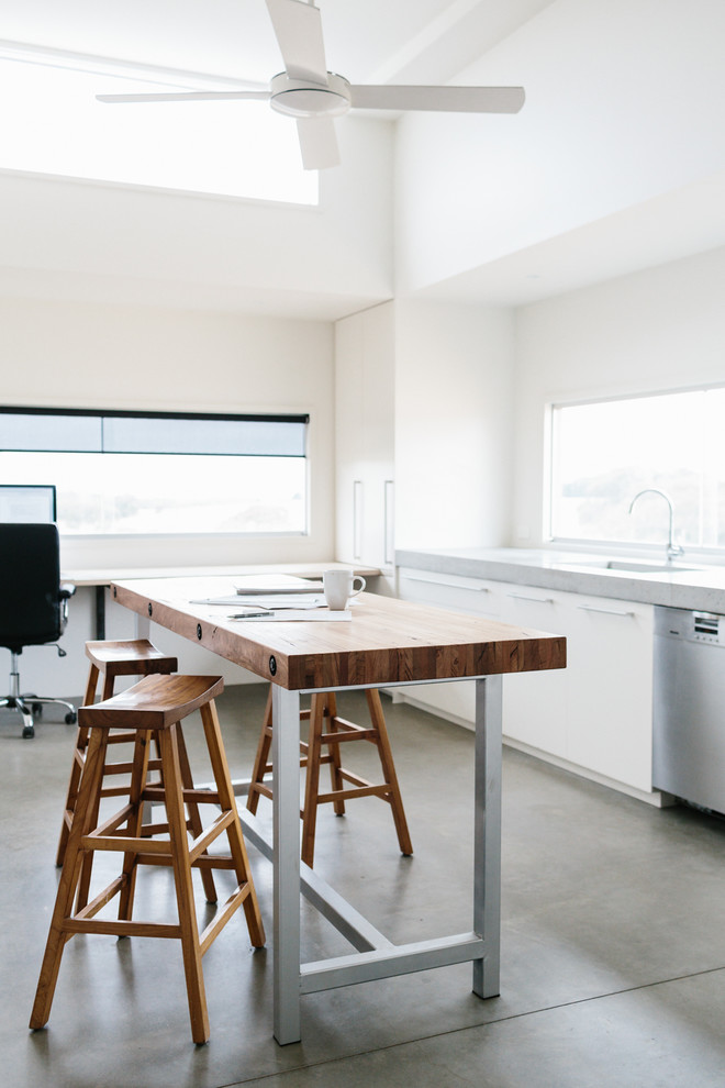 Modernes Arbeitszimmer mit weißer Wandfarbe, Betonboden und freistehendem Schreibtisch in Geelong
