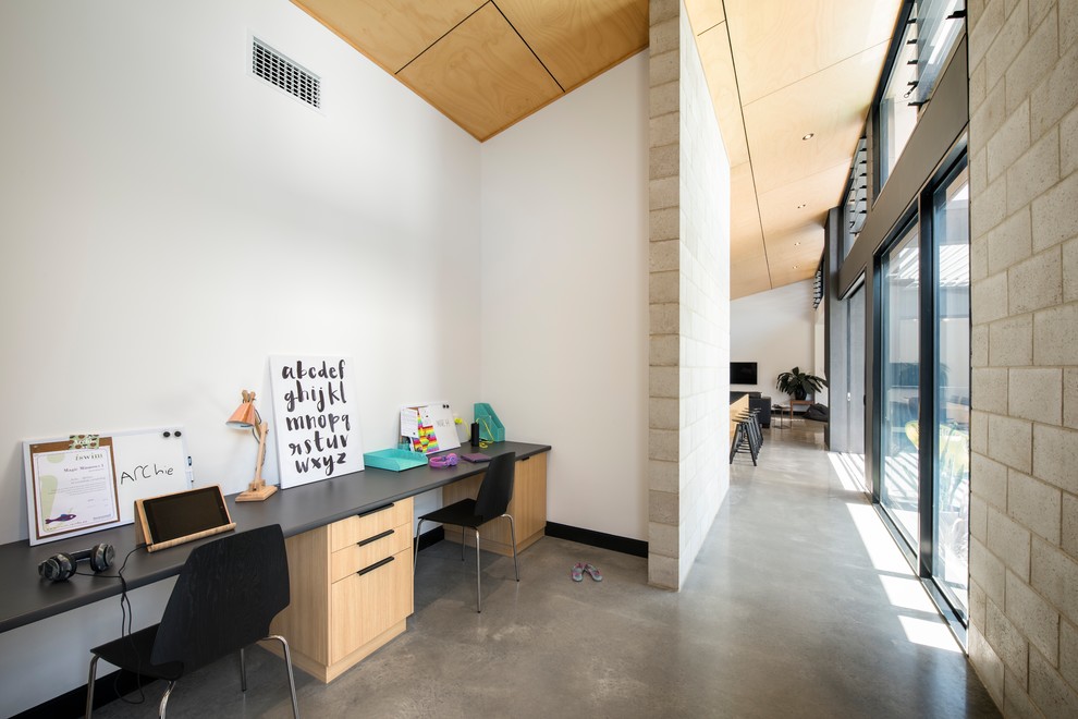 Mittelgroßes Modernes Arbeitszimmer mit Arbeitsplatz, weißer Wandfarbe, Betonboden und Einbau-Schreibtisch in Adelaide