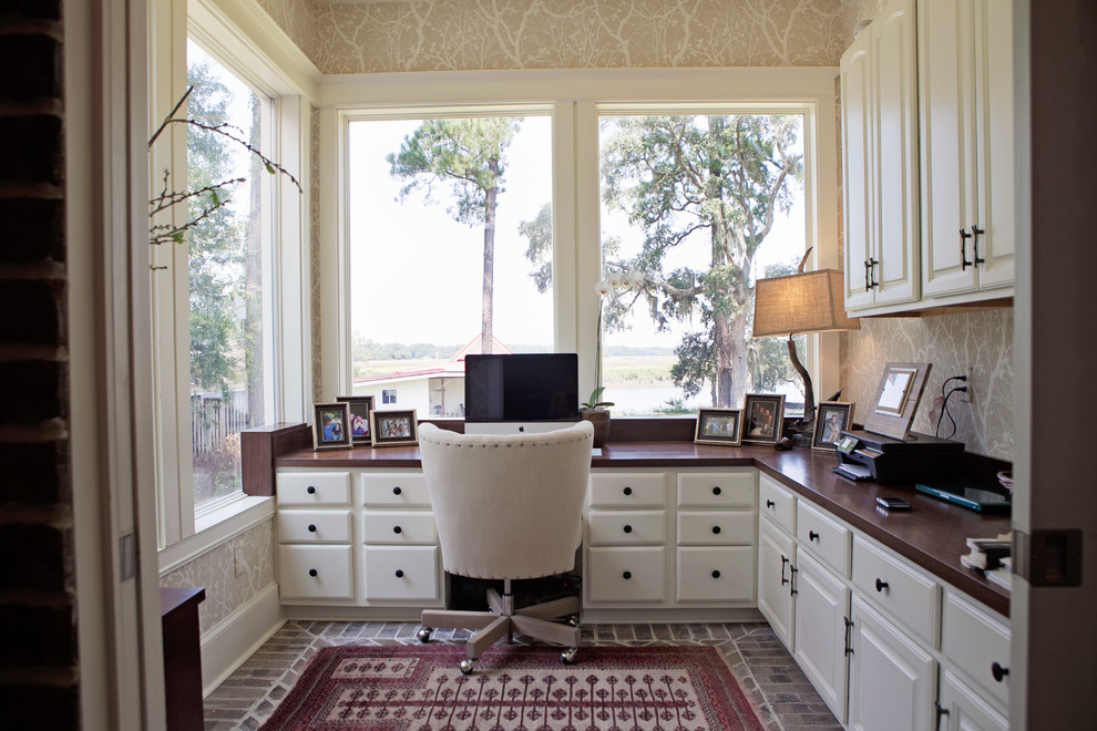 Cette image montre un bureau traditionnel de taille moyenne avec un mur beige, un sol en brique, aucune cheminée et un bureau intégré.