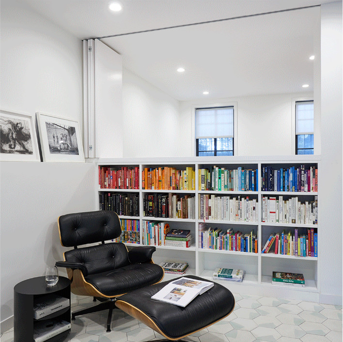 Modelo de despacho contemporáneo de tamaño medio con biblioteca, paredes blancas, suelo de cemento y suelo blanco