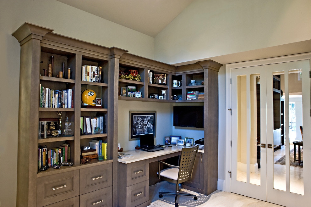 Immagine di uno studio minimal di medie dimensioni con libreria, pareti beige, pavimento in marmo, scrivania incassata e pavimento beige