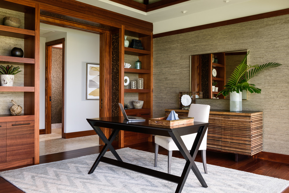 Großes Arbeitszimmer mit dunklem Holzboden, freistehendem Schreibtisch und beiger Wandfarbe in Hawaii