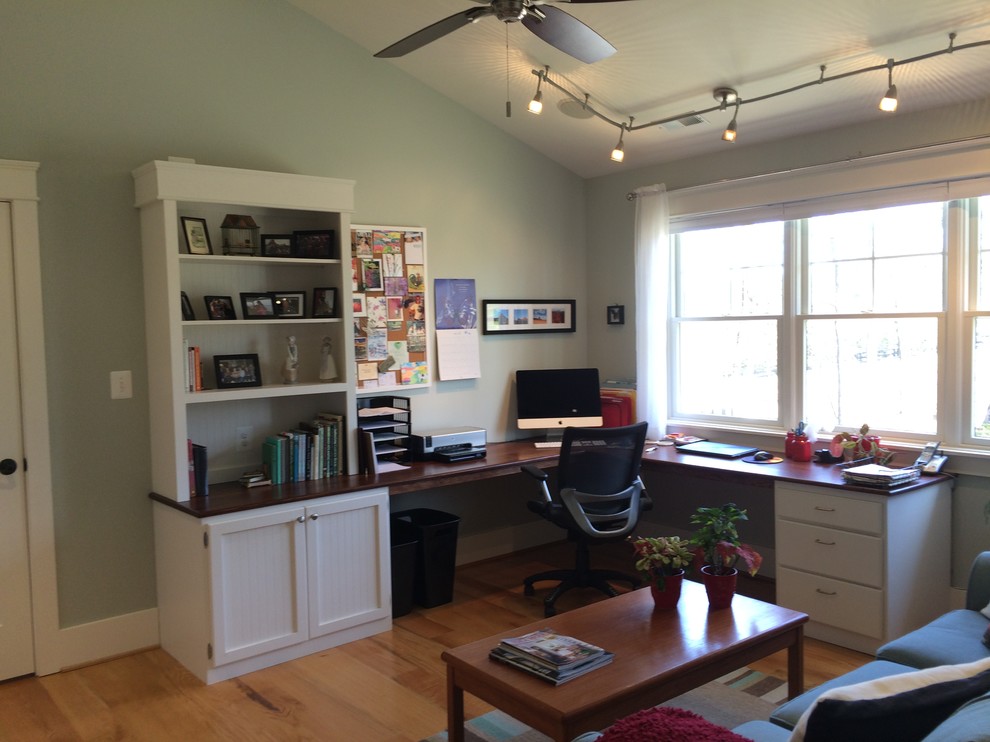 Exempel på ett amerikanskt arbetsrum, med blå väggar, ljust trägolv och ett inbyggt skrivbord