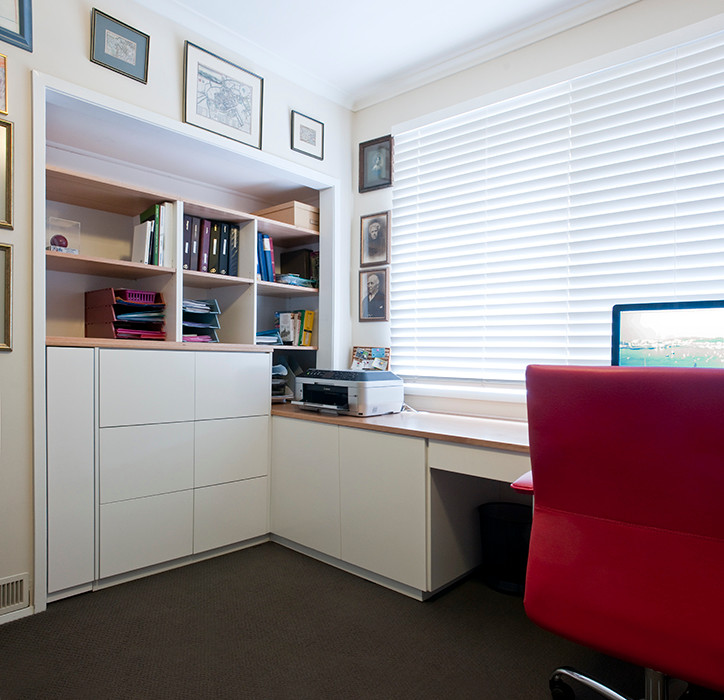 Immagine di un ampio ufficio minimal con pareti bianche, moquette, scrivania incassata e nessun camino