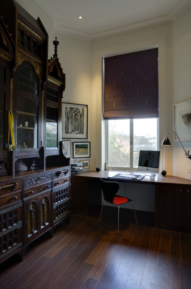 Photo of a medium sized contemporary study in London with white walls, dark hardwood flooring, no fireplace, a built-in desk and brown floors.