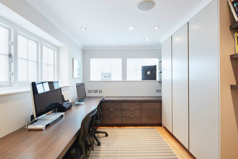 Großes Modernes Arbeitszimmer ohne Kamin mit Arbeitsplatz, weißer Wandfarbe, braunem Holzboden, Einbau-Schreibtisch und braunem Boden in London