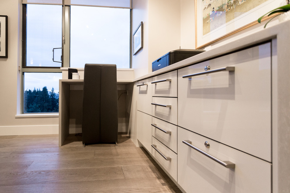 Foto di un piccolo ufficio minimalista con pareti beige, parquet chiaro e scrivania incassata
