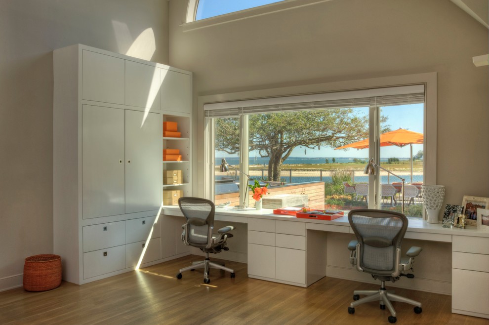 Home office - coastal built-in desk medium tone wood floor home office idea in New York with beige walls