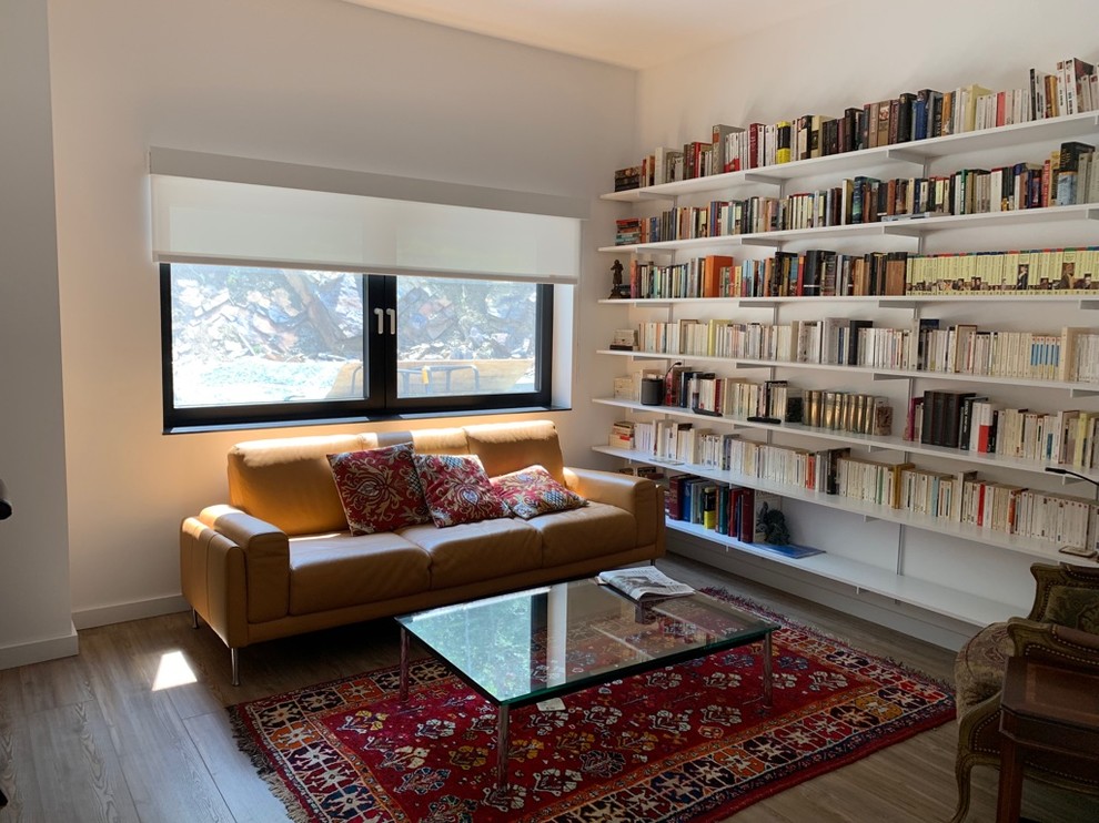 Cette photo montre un grand bureau moderne avec une bibliothèque ou un coin lecture, un mur blanc et un sol marron.