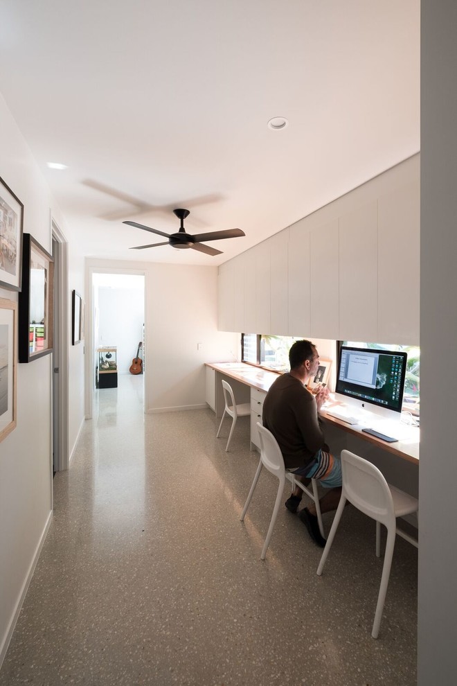 Home office - built-in desk concrete floor and gray floor home office idea in Gold Coast - Tweed with white walls