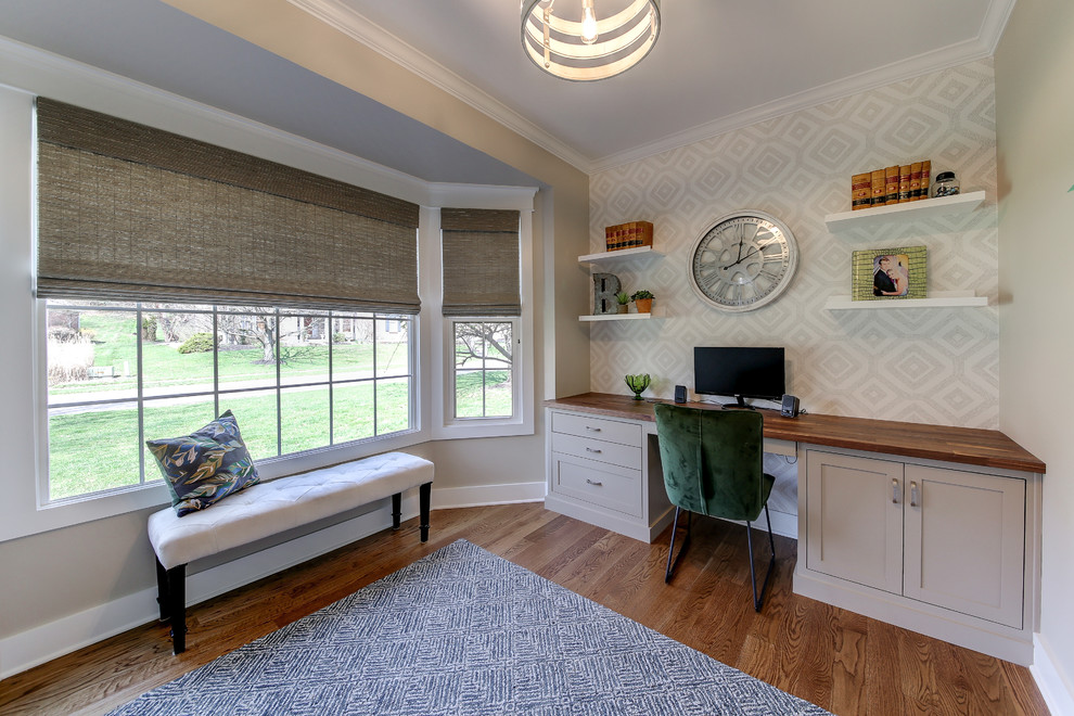 Foto de despacho tradicional renovado de tamaño medio sin chimenea con paredes grises, suelo de madera clara, escritorio empotrado y suelo marrón