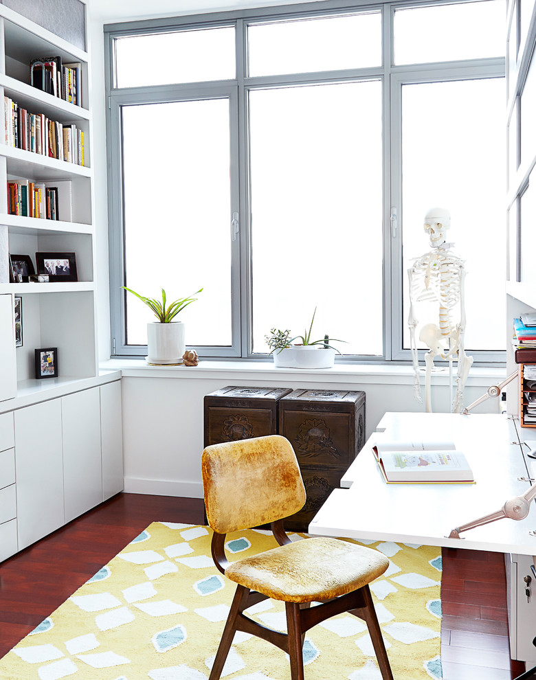 Kleines Modernes Arbeitszimmer ohne Kamin mit Arbeitsplatz, weißer Wandfarbe, braunem Holzboden und Einbau-Schreibtisch in New York