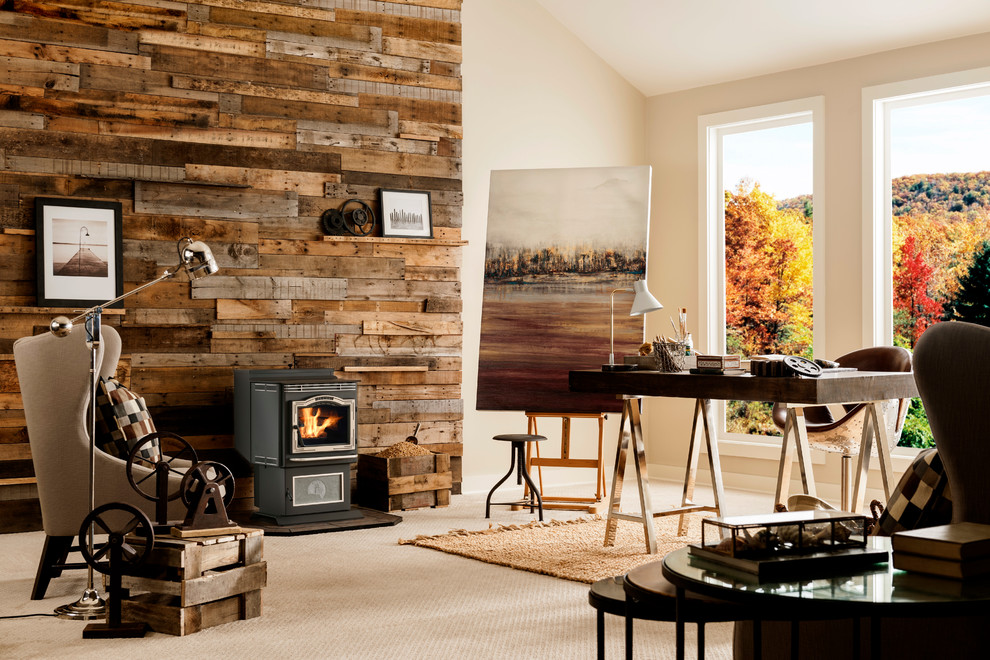 This is an example of a medium sized rustic study in New York with beige walls, carpet, a wood burning stove, a metal fireplace surround, a built-in desk and beige floors.