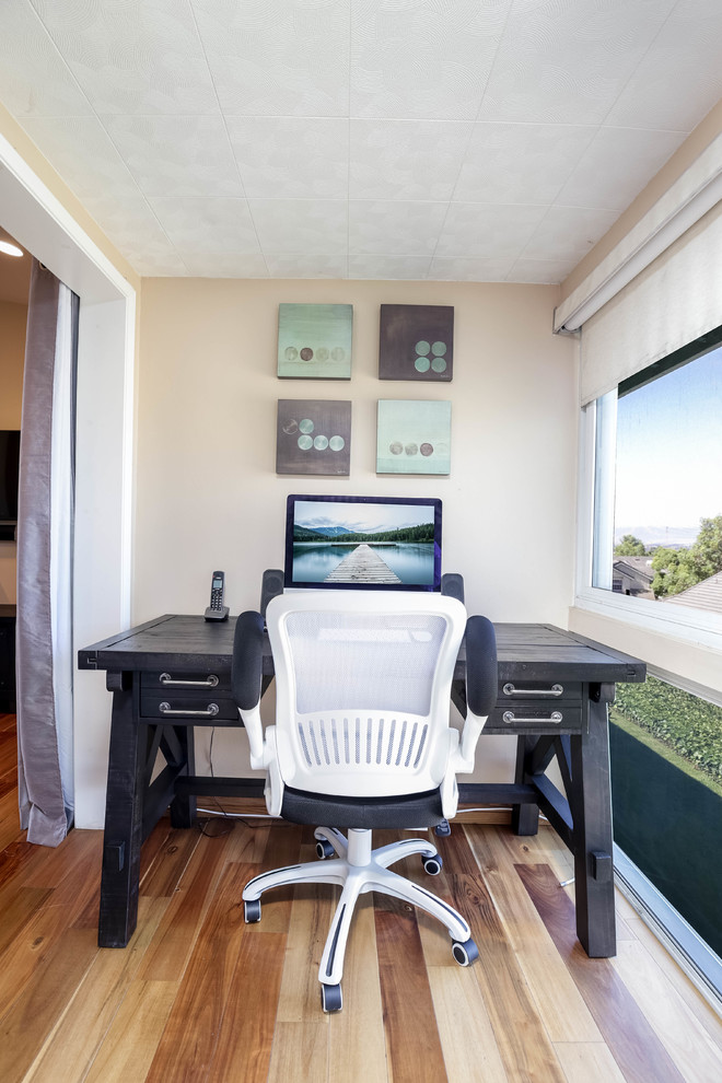 Foto di un piccolo ufficio moderno con pareti beige, parquet chiaro e scrivania autoportante