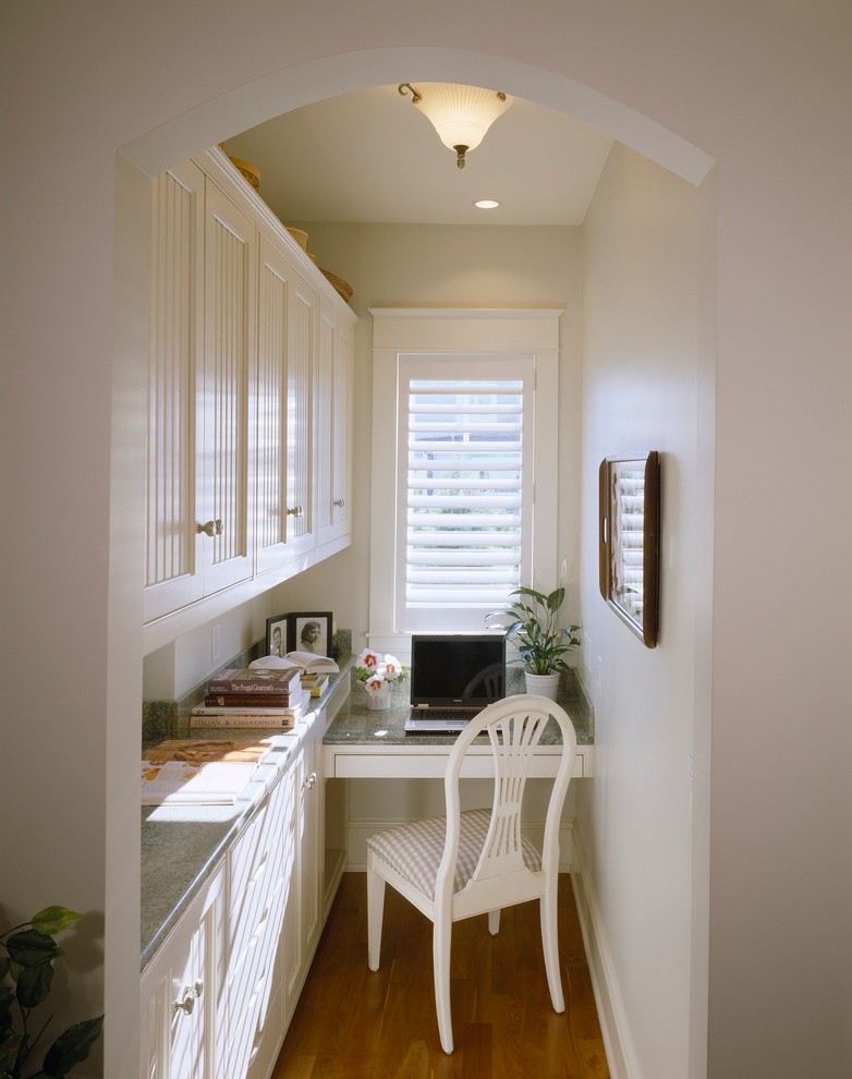 Kleines Shabby-Chic Arbeitszimmer ohne Kamin mit Arbeitsplatz, beiger Wandfarbe, Einbau-Schreibtisch, braunem Holzboden und braunem Boden in Portland Maine