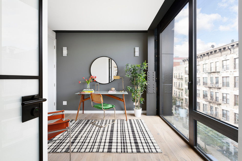 Modernes Arbeitszimmer mit grauer Wandfarbe, hellem Holzboden, freistehendem Schreibtisch und beigem Boden in New York