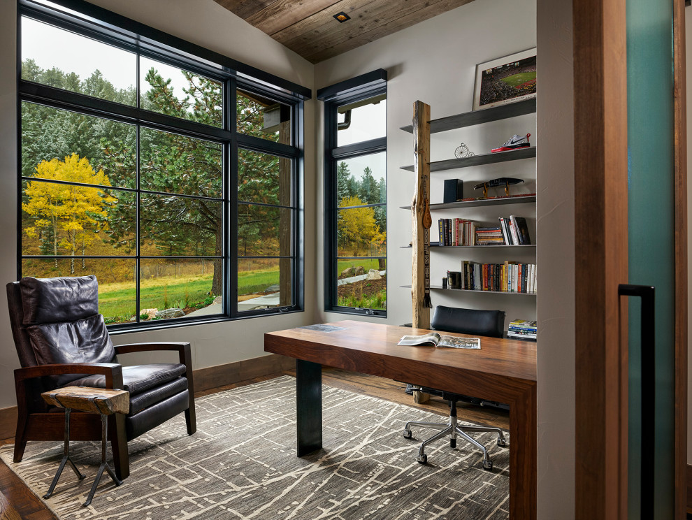 Diseño de despacho rústico de tamaño medio con paredes blancas, escritorio independiente, suelo marrón y suelo de madera oscura