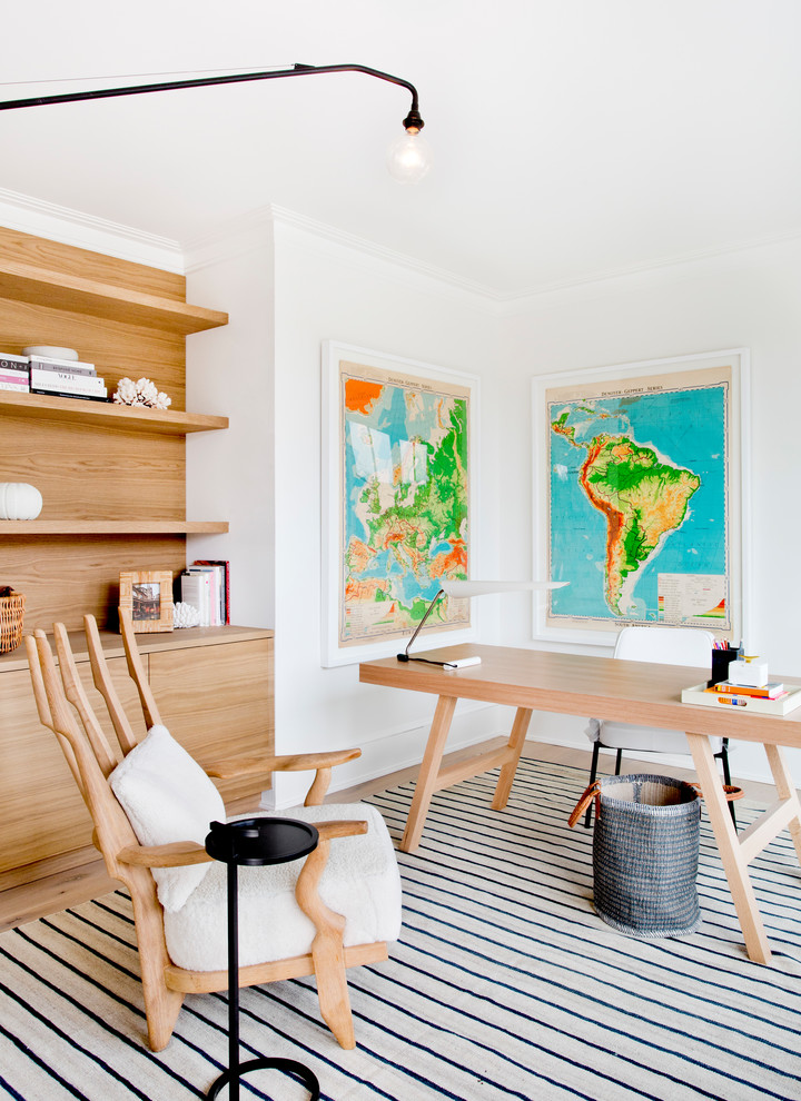 Inspiration för stora minimalistiska hemmabibliotek, med vita väggar, ljust trägolv, ett fristående skrivbord och beiget golv