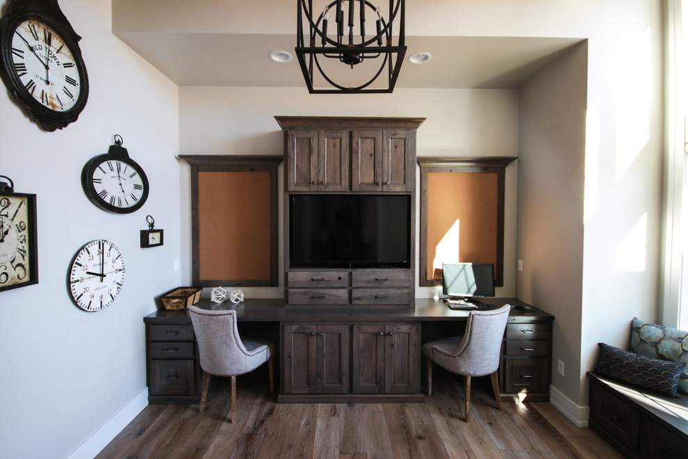 Modelo de despacho tradicional de tamaño medio sin chimenea con paredes grises, suelo de madera en tonos medios y escritorio independiente