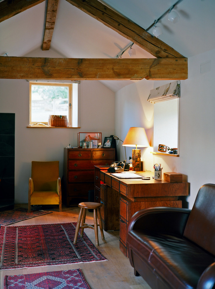 Ejemplo de despacho campestre con paredes blancas, suelo de madera clara y escritorio independiente