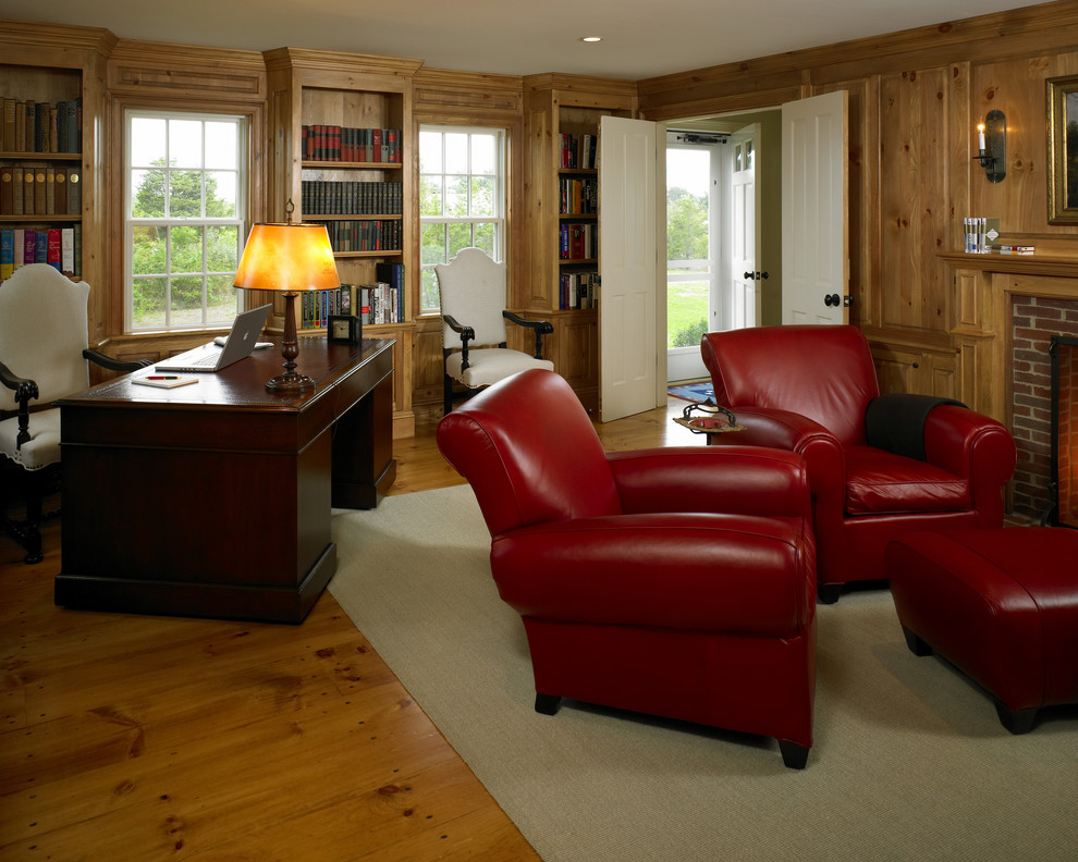 Design ideas for a medium sized rural study in Boston with brown walls, medium hardwood flooring, a standard fireplace, a brick fireplace surround and a freestanding desk.