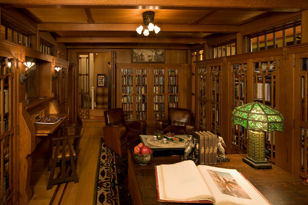 Foto på ett mycket stort amerikanskt hemmabibliotek, med bruna väggar, mörkt trägolv och ett inbyggt skrivbord
