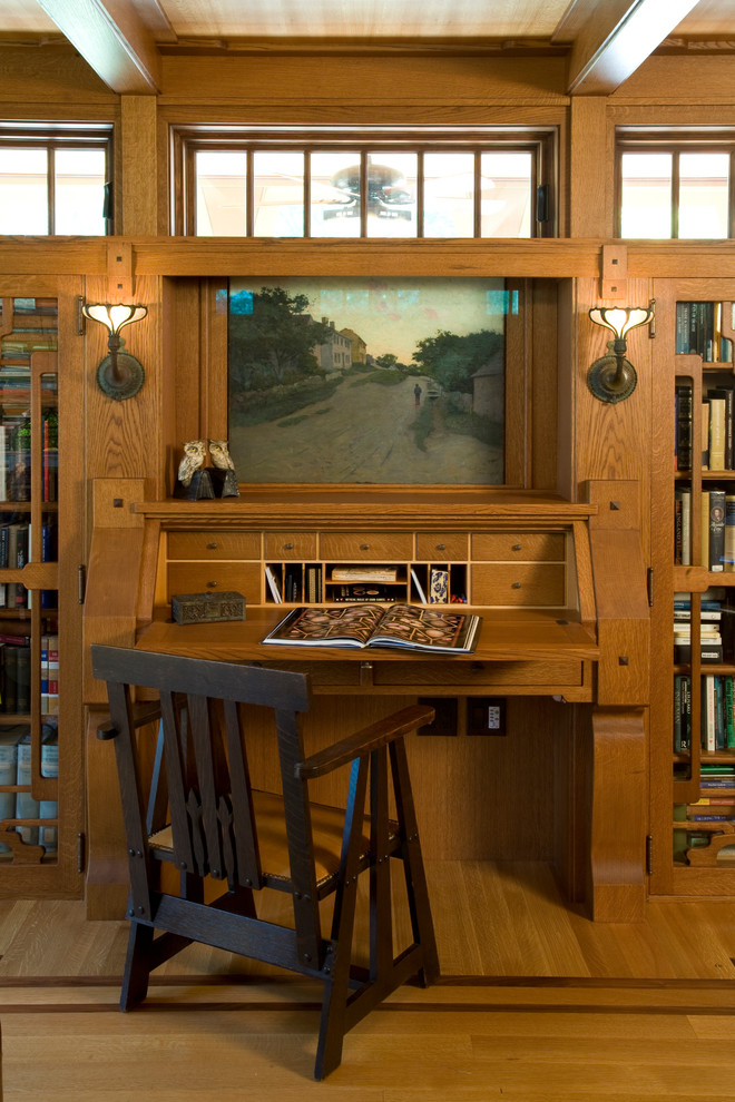Diseño de despacho de estilo americano grande sin chimenea con suelo de madera en tonos medios, escritorio empotrado y paredes marrones