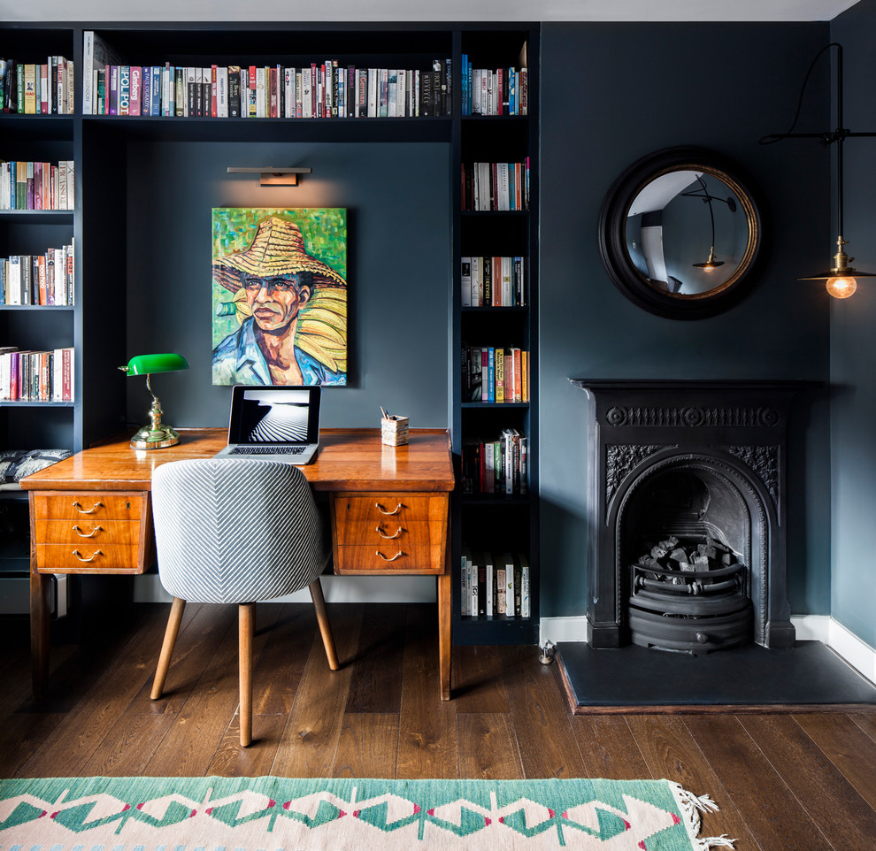 ロンドンにある小さなエクレクティックスタイルのおしゃれなホームオフィス・書斎 (黒い壁、濃色無垢フローリング、標準型暖炉、金属の暖炉まわり、茶色い床、ライブラリー) の写真