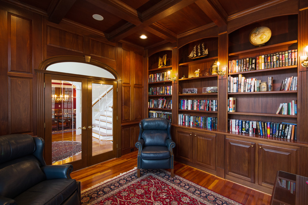 Ejemplo de despacho clásico de tamaño medio sin chimenea con suelo de madera en tonos medios, escritorio independiente, biblioteca y paredes marrones