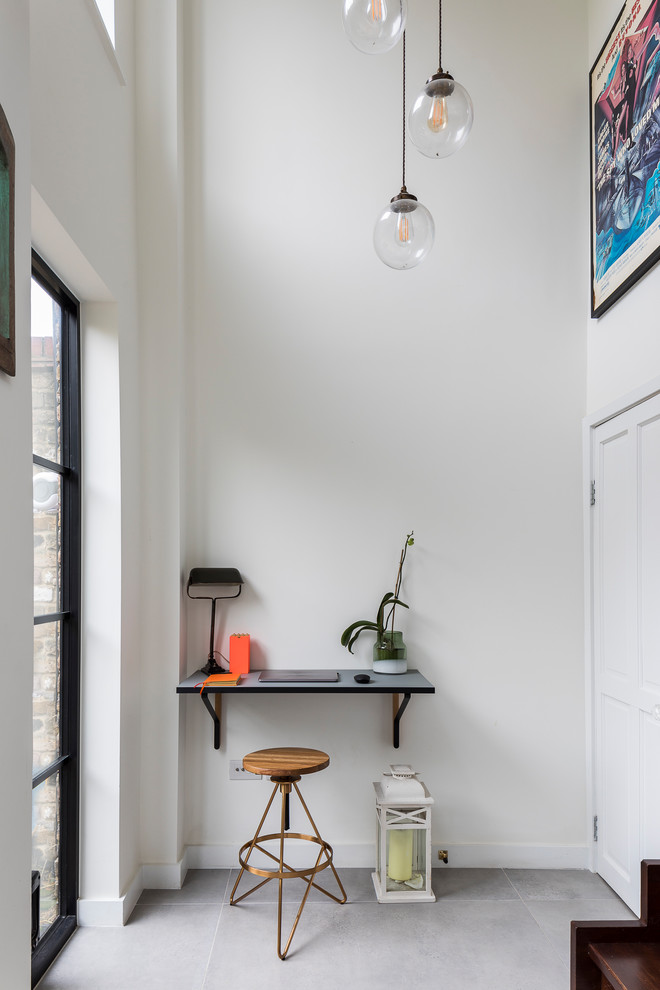 Photo of a small traditional study in London with white walls, ceramic flooring, no fireplace, a built-in desk and grey floors.