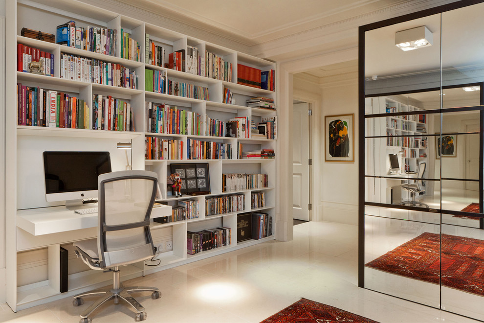 Idéer för ett modernt hemmabibliotek, med vita väggar, ett inbyggt skrivbord och beiget golv