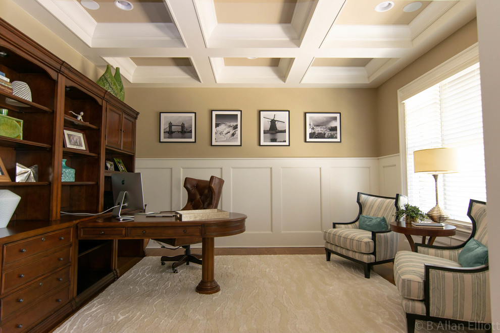 Imagen de despacho tradicional renovado de tamaño medio con paredes amarillas, suelo de madera en tonos medios, escritorio independiente y suelo marrón