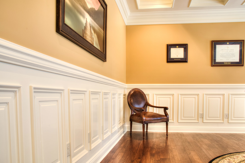 Klassisches Arbeitszimmer mit Arbeitsplatz, freistehendem Schreibtisch, brauner Wandfarbe und braunem Holzboden in Sonstige